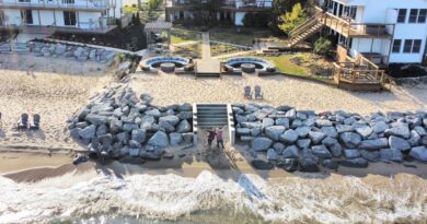 aerial view of three white two story resorts on a beach with brick fire pits and circular seating.jpg