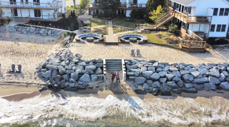 aerial view of three white two story resorts on a beach with brick fire pits and circular seating.jpg