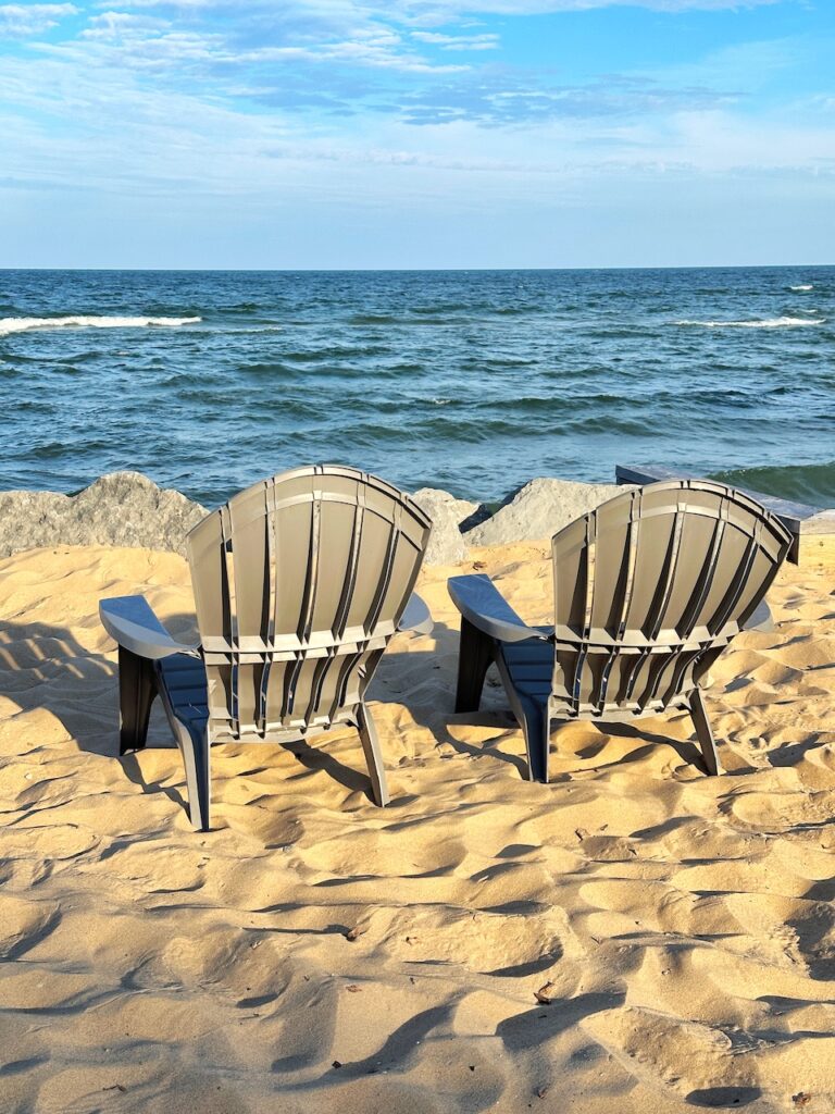 gray lounge chairs on sandy beach overlooking Lake Huron